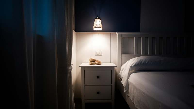 Person peacefully sleeping in a dimly lit bedroom with soft blue bedding and calming ambient light