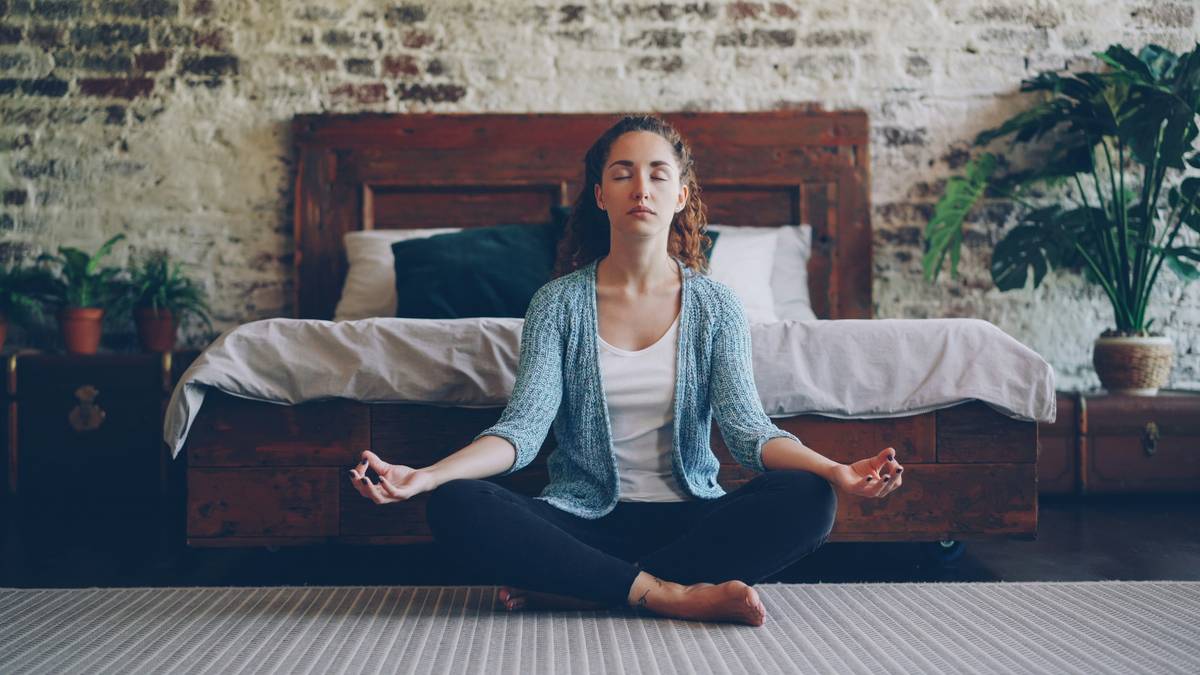 Woman practicing deep breathing in bed as part of relaxation technique insomnia relief remedy to reduce nighttime anxiety